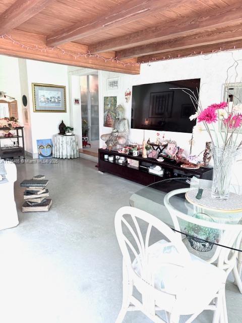 living room featuring beamed ceiling, wood ceiling, finished concrete flooring, and visible vents