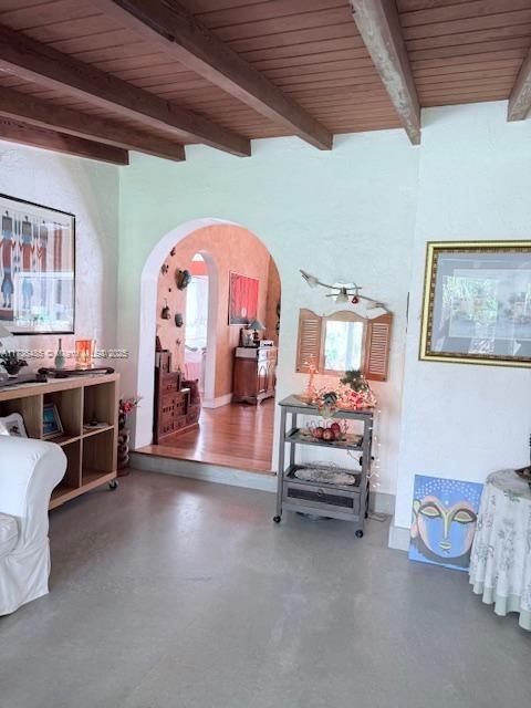 interior space with a wealth of natural light, arched walkways, concrete flooring, and wood ceiling