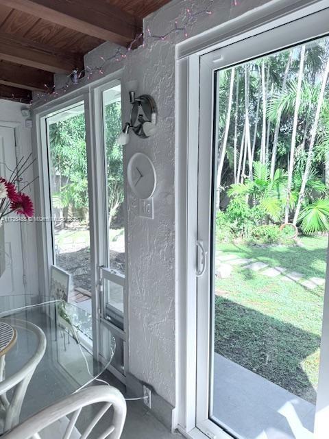 1643 Nethia Dr, Miami, FL 33133 - doorway to outside featuring a textured wall, beam ceiling, and a wealth of natural light