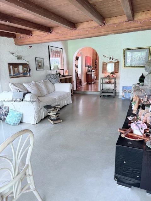 living area with arched walkways, beamed ceiling, wood ceiling, and concrete flooring