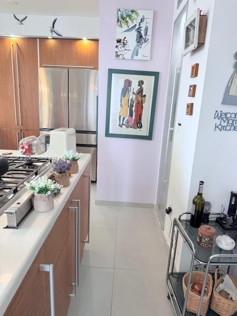 1643 Nethia Dr, Miami, FL 33133 - kitchen with freestanding refrigerator, light countertops, light tile patterned floors, and brown cabinets