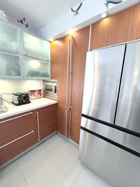 kitchen with stainless steel appliances, brown cabinetry, and light countertops