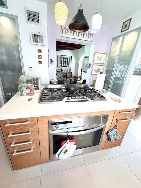 kitchen featuring visible vents, stainless steel appliances, tile patterned flooring, light countertops, and decorative light fixtures