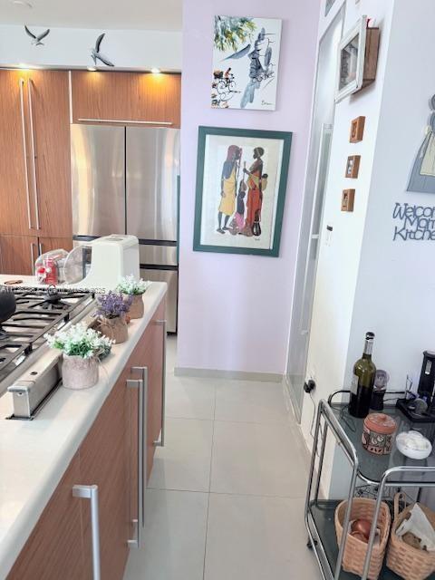 kitchen featuring light countertops, light tile patterned floors, brown cabinets, stainless steel appliances, and modern cabinets