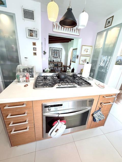 1643 Nethia Dr, Miami, FL 33133 - kitchen with light countertops, appliances with stainless steel finishes, tile patterned flooring, visible vents, and decorative light fixtures