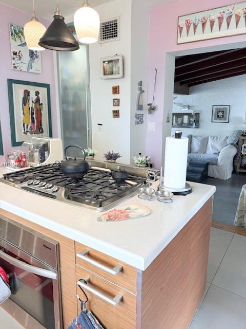1643 Nethia Dr, Miami, FL 33133 - kitchen with stainless steel appliances, light countertops, light tile patterned floors, decorative light fixtures, and open floor plan