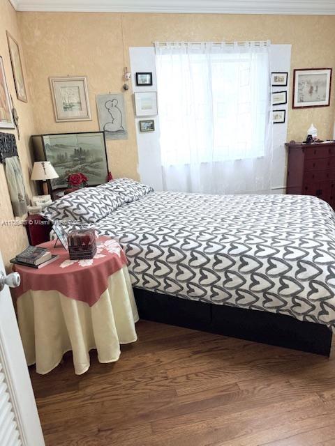 bedroom featuring wood finished floors and ornamental molding