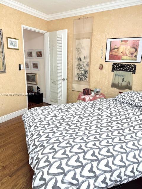 bedroom featuring baseboards, wood finished floors, and ornamental molding