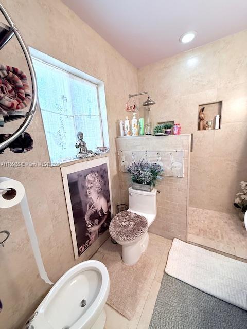 full bathroom featuring tile patterned floors, toilet, a tile shower, and tile walls