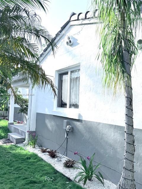 1643 Nethia Dr, Miami, FL 33133 - view of side of home with stucco siding and a yard