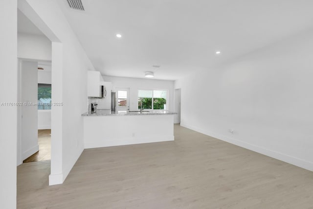 unfurnished living room featuring visible vents, baseboards, and light wood-style floors