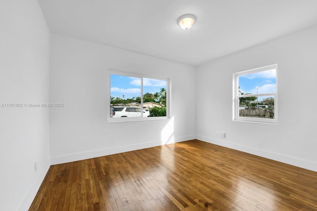 empty room with baseboards, a healthy amount of sunlight, and hardwood / wood-style floors