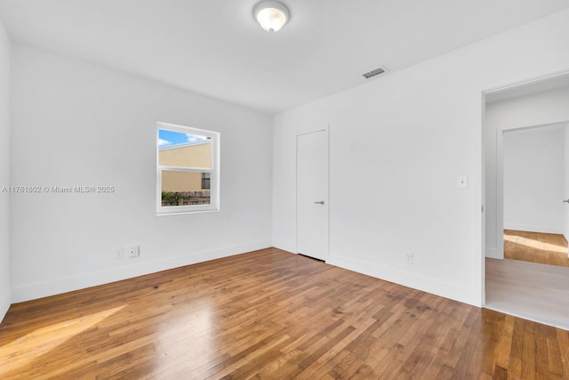 spare room featuring visible vents, baseboards, and hardwood / wood-style flooring