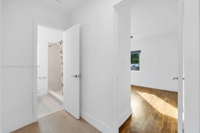 hallway featuring baseboards and wood finished floors