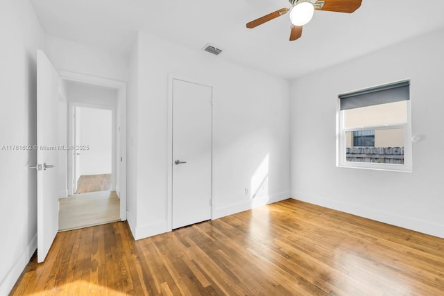 unfurnished bedroom with visible vents, baseboards, ceiling fan, and hardwood / wood-style flooring