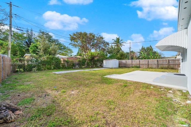 view of yard featuring a patio area, a storage unit, a fenced backyard, and an outdoor structure