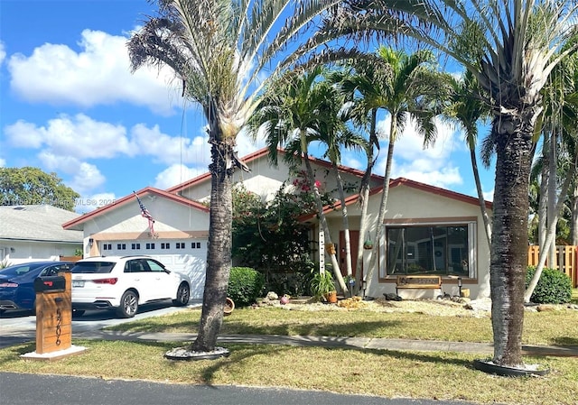 view of front of property featuring a garage, a front yard, driveway, and stucco siding