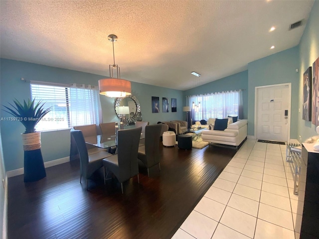 dining space featuring visible vents, lofted ceiling, a textured ceiling, and wood finished floors