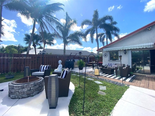 view of yard featuring an outdoor living space with a fire pit, a deck, and fence