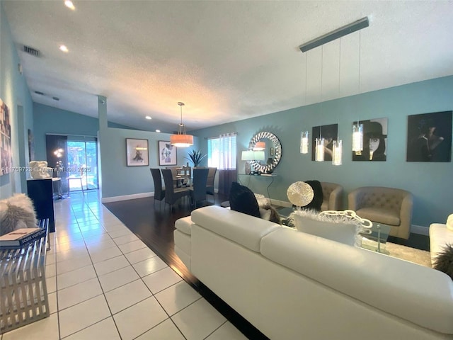 living room with visible vents, a textured ceiling, baseboards, light tile patterned flooring, and lofted ceiling