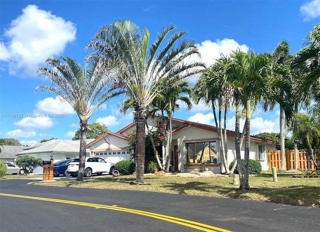 view of front of property featuring an attached garage, driveway, and fence