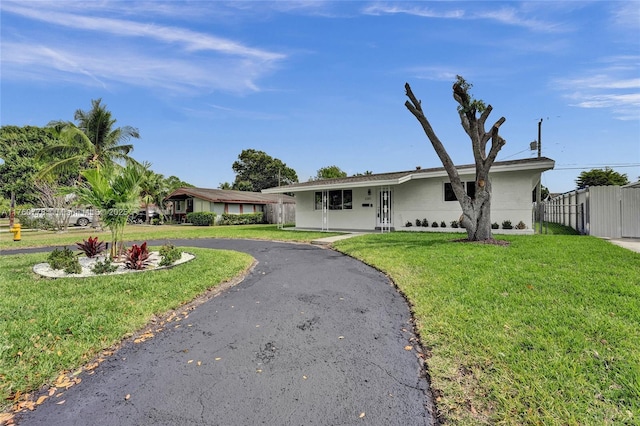 ranch-style home with driveway, a front lawn, and fence