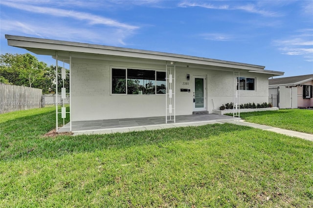 view of front of house featuring brick siding, a front yard, and fence