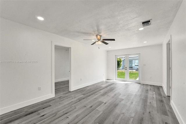 empty room with recessed lighting, wood finished floors, baseboards, and french doors