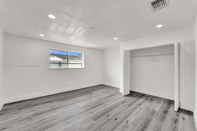 unfurnished bedroom with visible vents, recessed lighting, baseboards, and wood finished floors