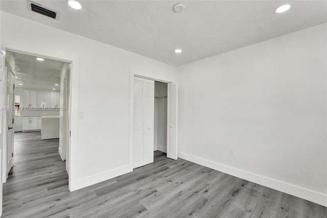 unfurnished bedroom with visible vents, baseboards, recessed lighting, light wood-style flooring, and a closet