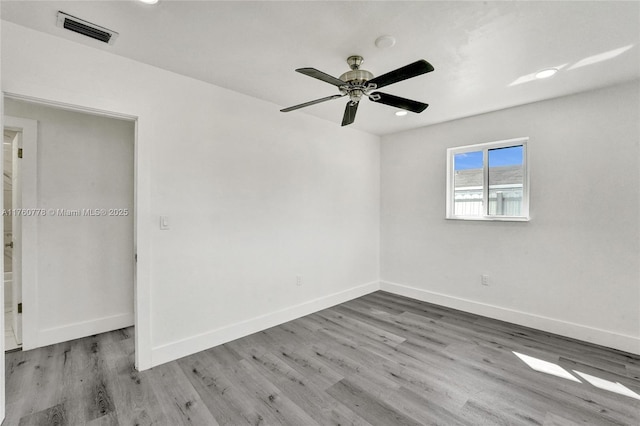 spare room with visible vents, baseboards, and wood finished floors