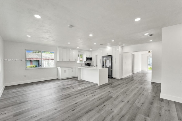 kitchen with light wood-type flooring, open floor plan, white cabinetry, recessed lighting, and stainless steel appliances