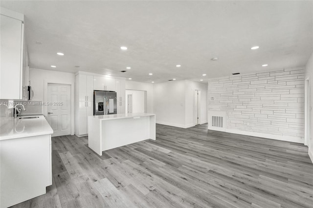 kitchen with visible vents, a sink, a kitchen island, stainless steel appliances, and white cabinets