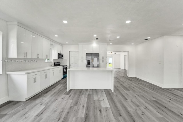 kitchen featuring light wood finished floors, white cabinetry, appliances with stainless steel finishes, and a kitchen island