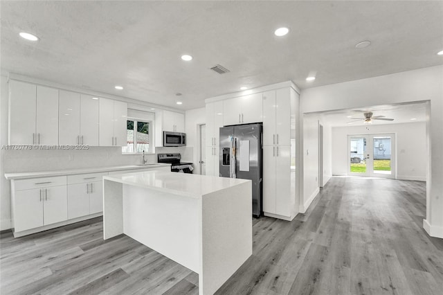 kitchen with a sink, visible vents, appliances with stainless steel finishes, and white cabinetry