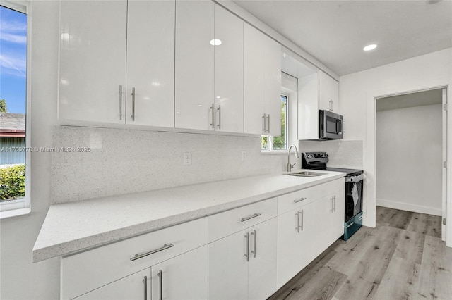 kitchen featuring a sink, decorative backsplash, white cabinets, and stainless steel appliances