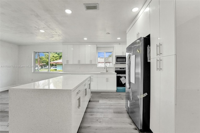 kitchen featuring light wood-type flooring, visible vents, modern cabinets, a sink, and stainless steel appliances