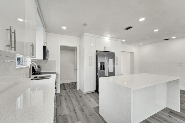 kitchen with visible vents, modern cabinets, appliances with stainless steel finishes, white cabinets, and light wood finished floors