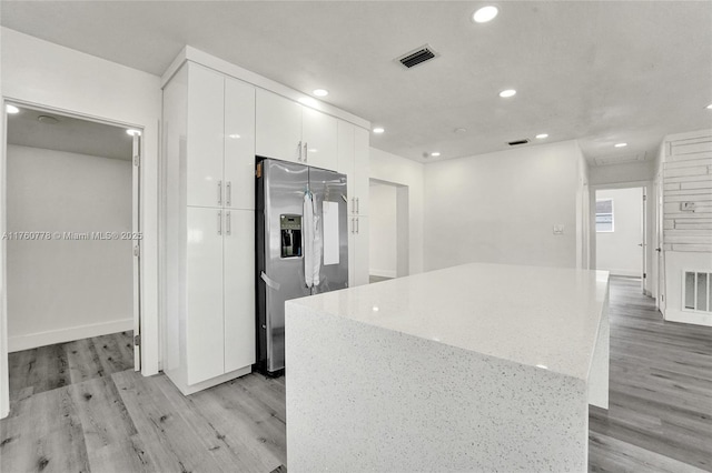 kitchen featuring visible vents, white cabinets, light wood-style floors, and stainless steel refrigerator with ice dispenser