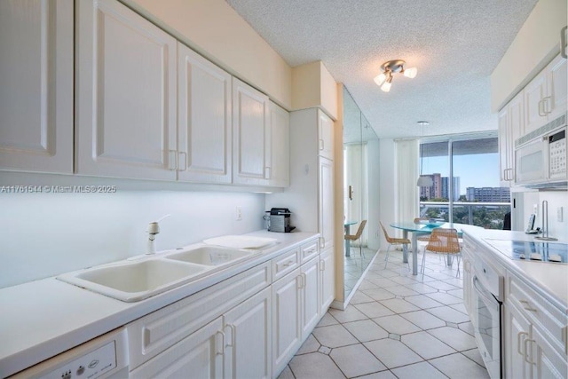 kitchen with white cabinetry, white appliances, and a sink