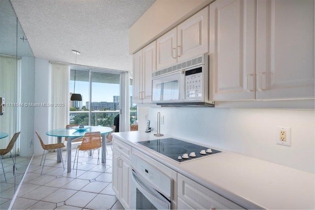 kitchen featuring floor to ceiling windows, light countertops, light tile patterned flooring, white appliances, and a textured ceiling