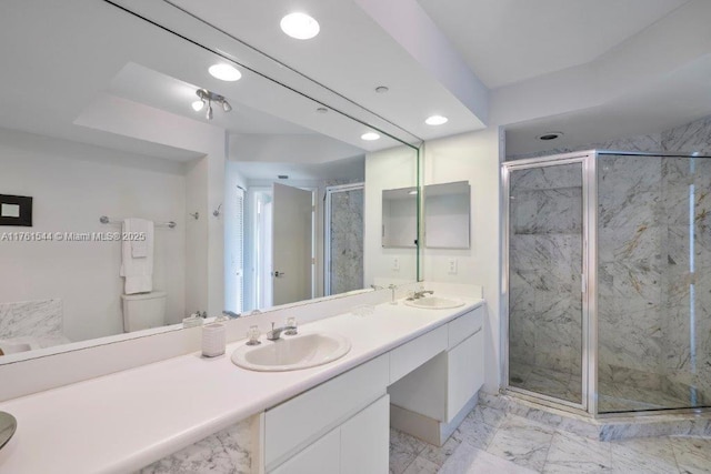 bathroom with double vanity, a stall shower, marble finish floor, and a sink