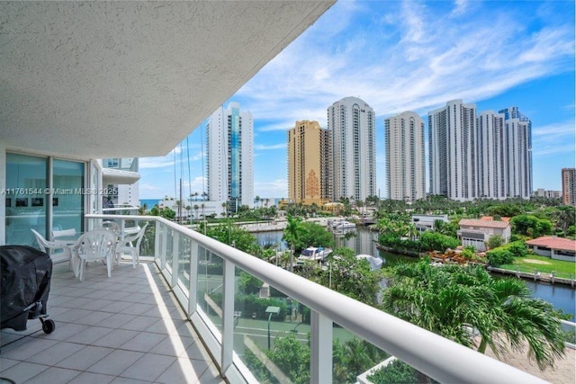 balcony featuring a city view, a water view, and a grill