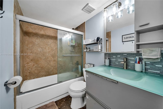 bathroom with visible vents, toilet, decorative backsplash, combined bath / shower with glass door, and vanity
