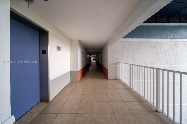hallway featuring elevator and tile patterned flooring