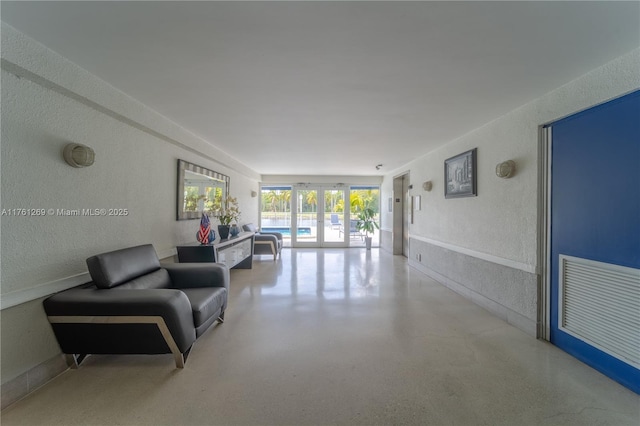 interior space featuring french doors, speckled floor, and a textured wall