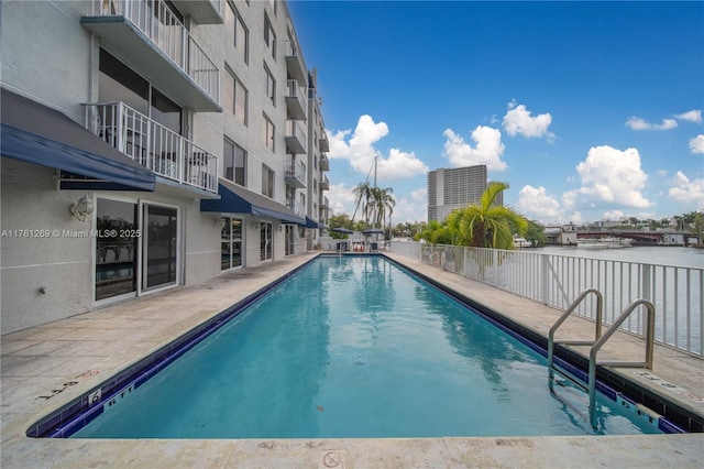 pool featuring a patio area and a water view
