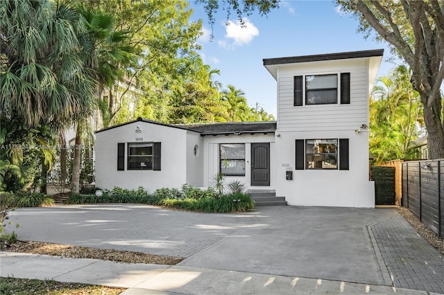 view of front of house featuring stucco siding, entry steps, and fence