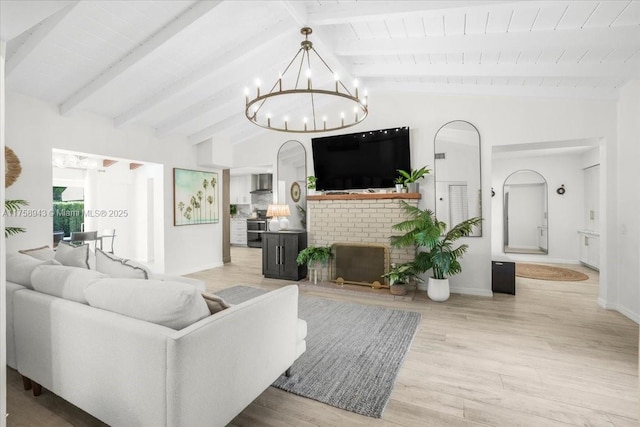 living room featuring lofted ceiling with beams, light wood-style floors, an inviting chandelier, baseboards, and a brick fireplace