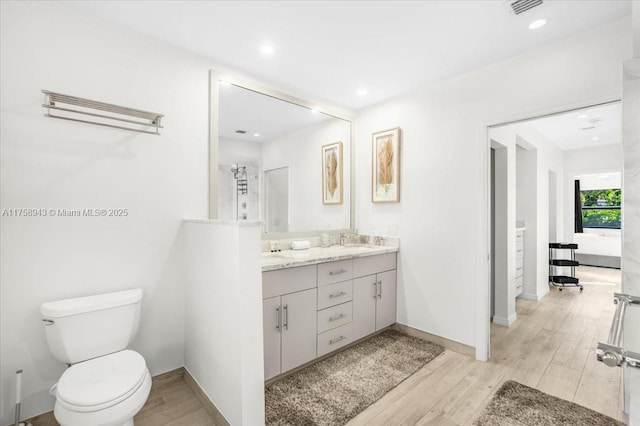 bathroom featuring a sink, toilet, wood finished floors, and double vanity